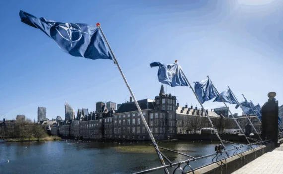 Rij blauwe NAVO-vlaggen langs de Hofvijver voor het Binnenhof in Den Haag onder een heldere blauwe lucht